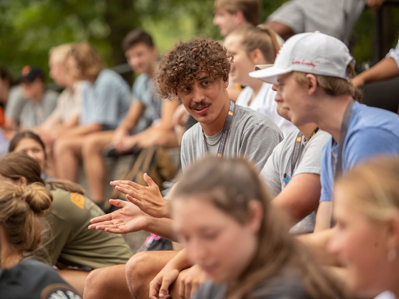 Two male students converse amongst a group of new students.