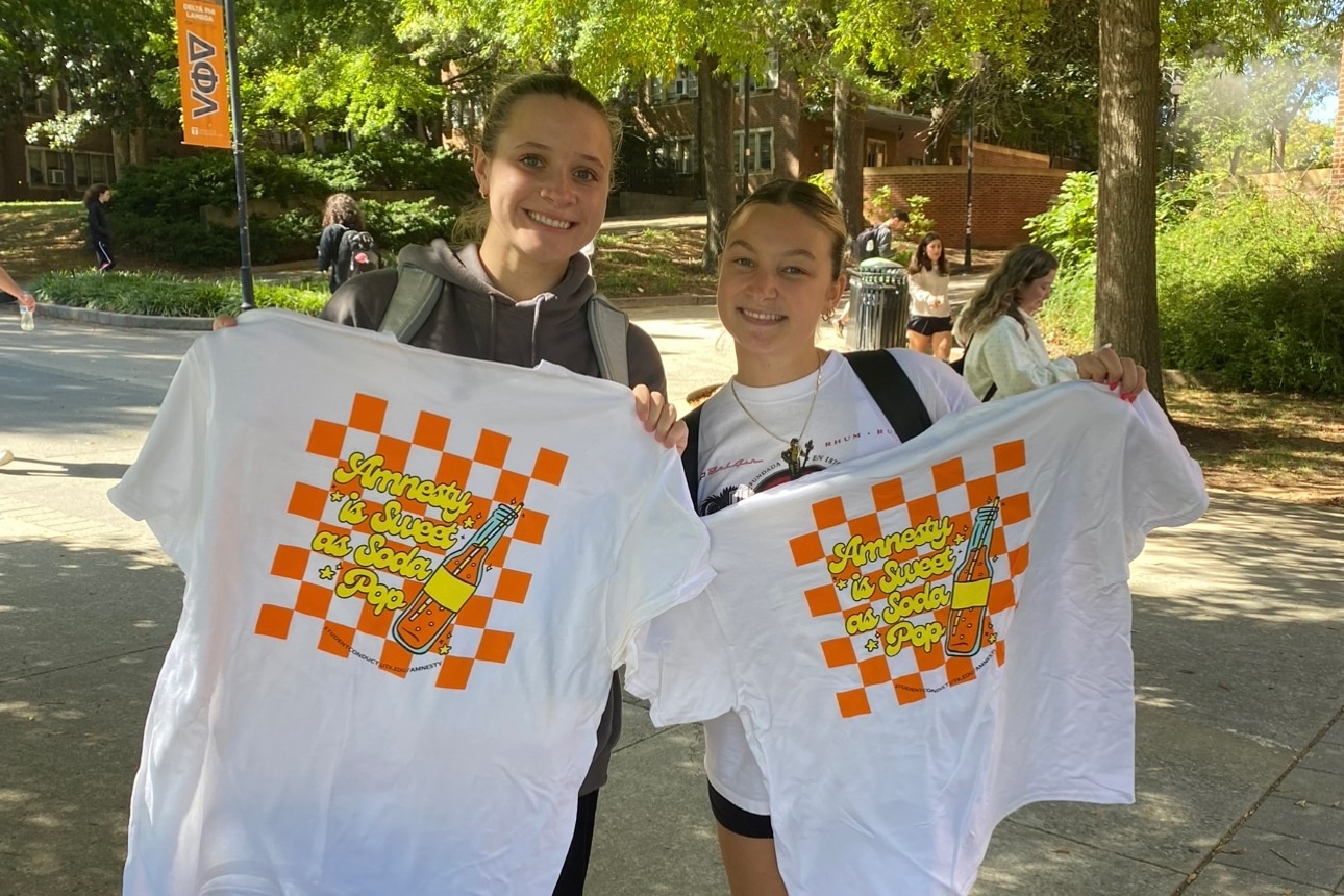 two students holding up t-shirts