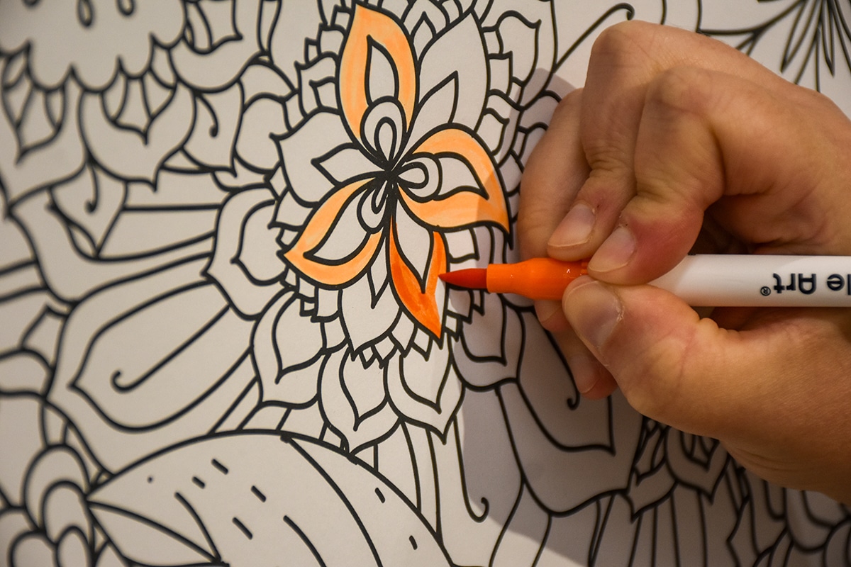 a person's hand coloring a flower in a coloring book