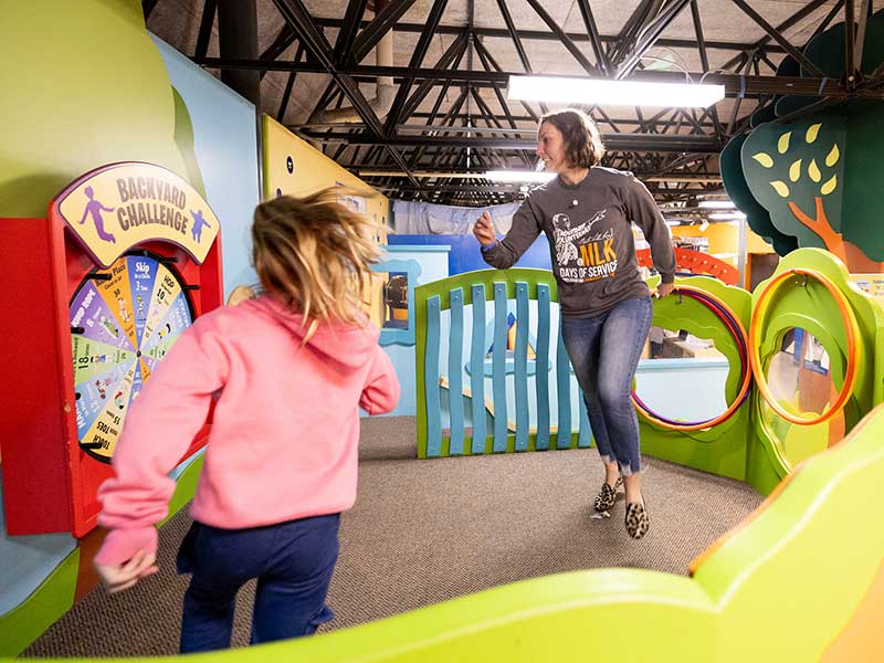 A volunteer skips with a young child as part of an activity at The Muse children's museum.
