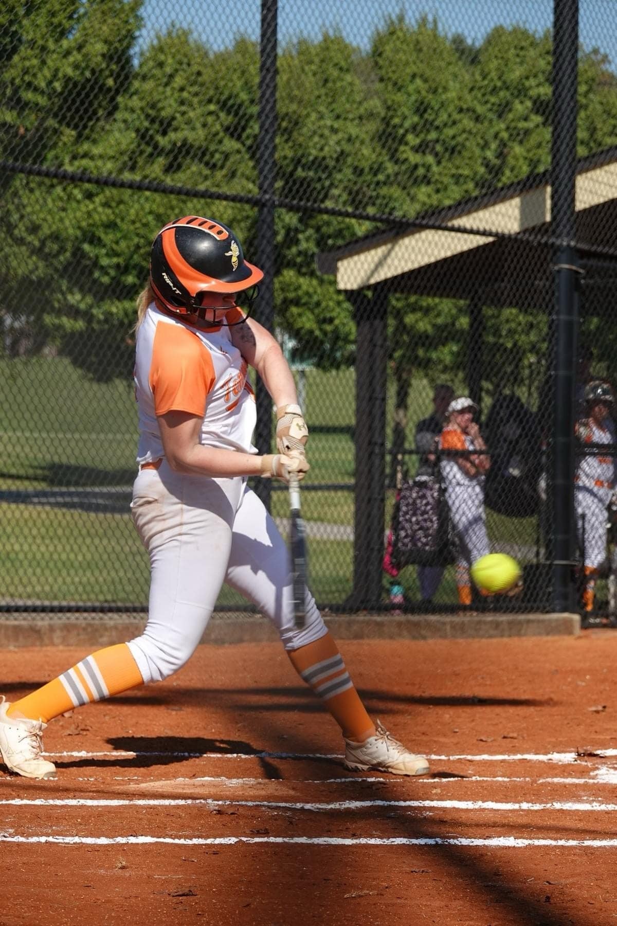 a person in a softball uniform hitting a softball 