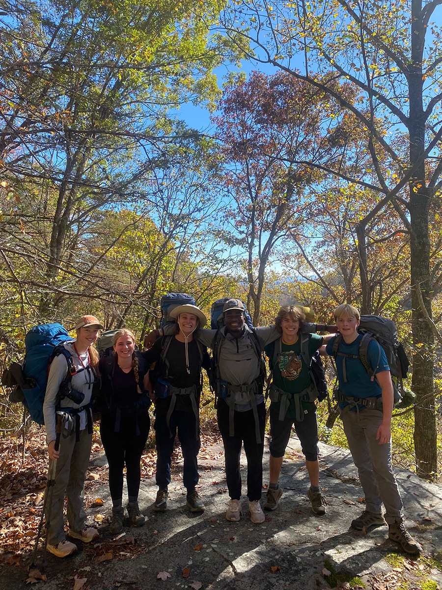 a group of people in the woods pose for a group photo