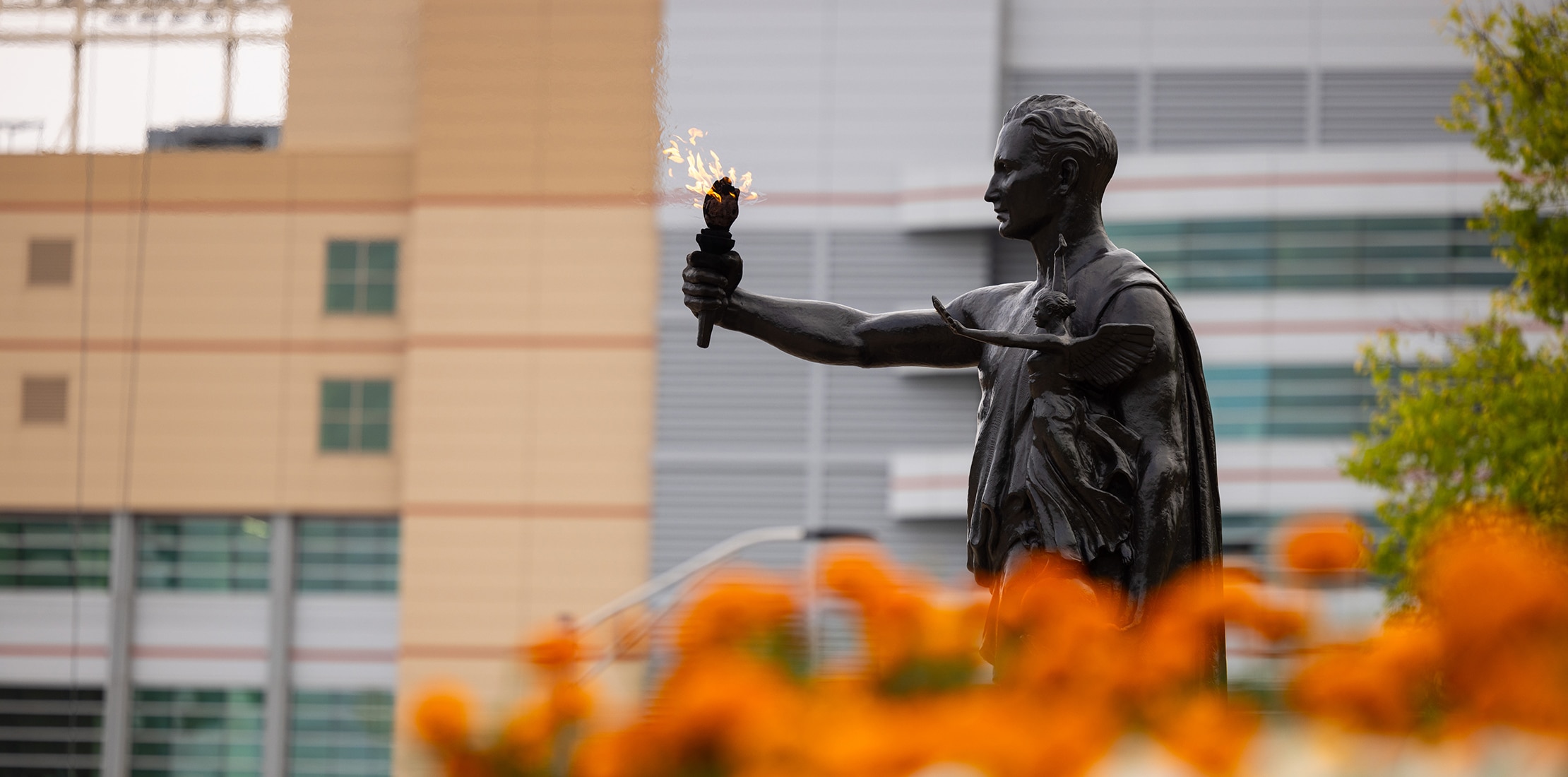 torchbearer statue with orange flowers in front and Neyland Stadium in the background