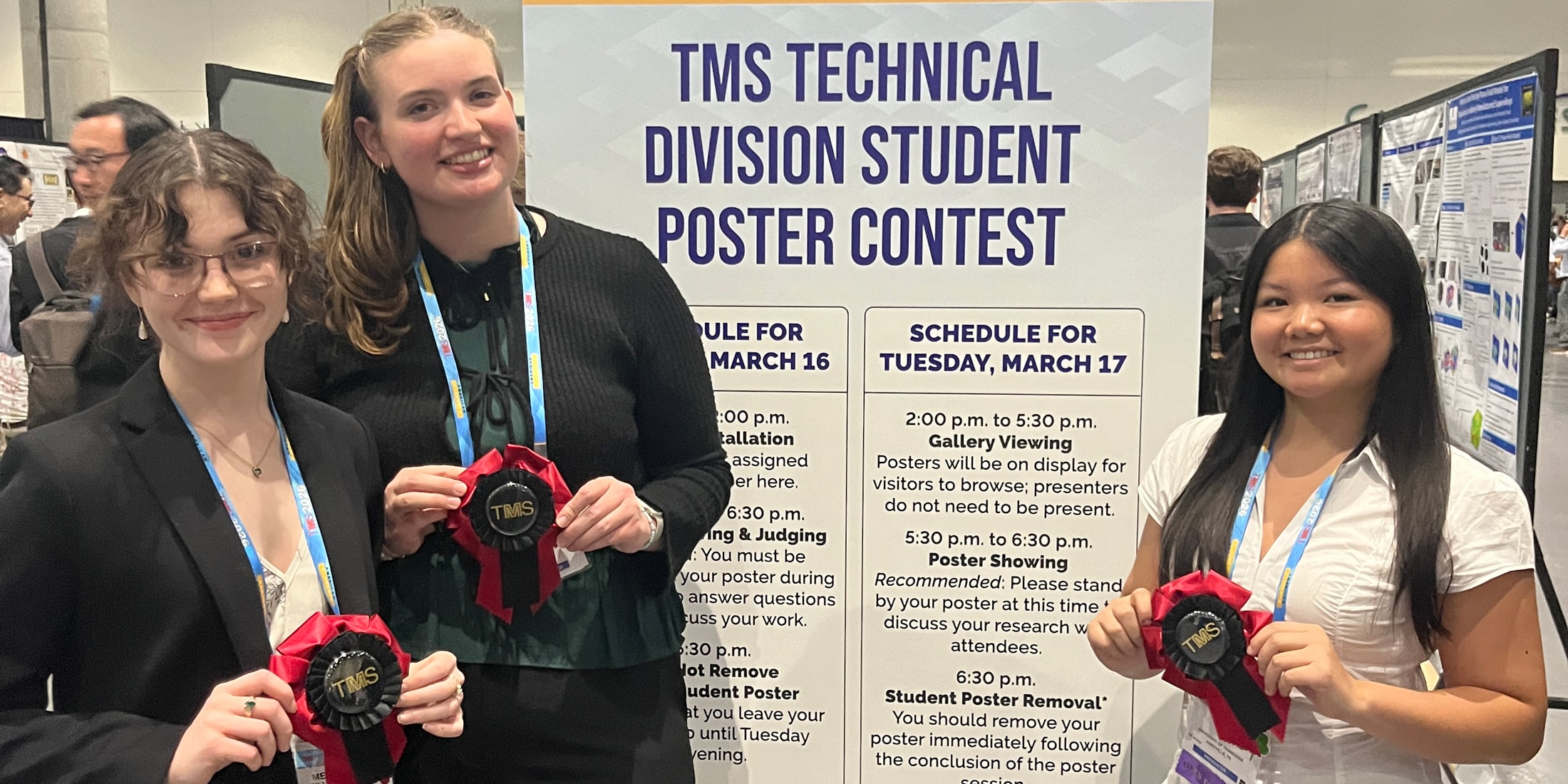 Three students stand in front of poster.